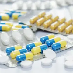 Leki w blistrach i tabletki. Niektóre kapsułki mają żółto-niebieskie paski, inne są białe. Mogą pomóc w walce z akatyzją.