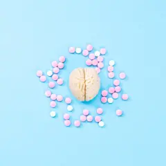 Model mózgu otoczony różowymi i białymi tabletkami, symbolizującymi leczenie SSRI.