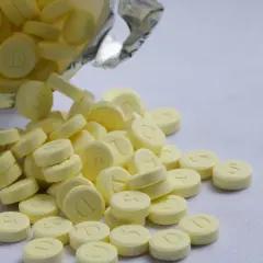 Żółte tabletki, niektóre z literą "D", inne z cyfrą "5", wysypują się z białego opakowania. To może być relanium.