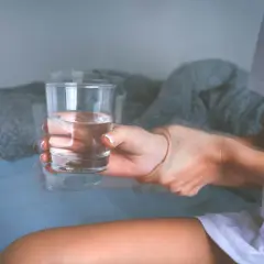 Drżąca ręka trzymająca szklankę wody, symbolizująca objawy padaczki alkoholowej.