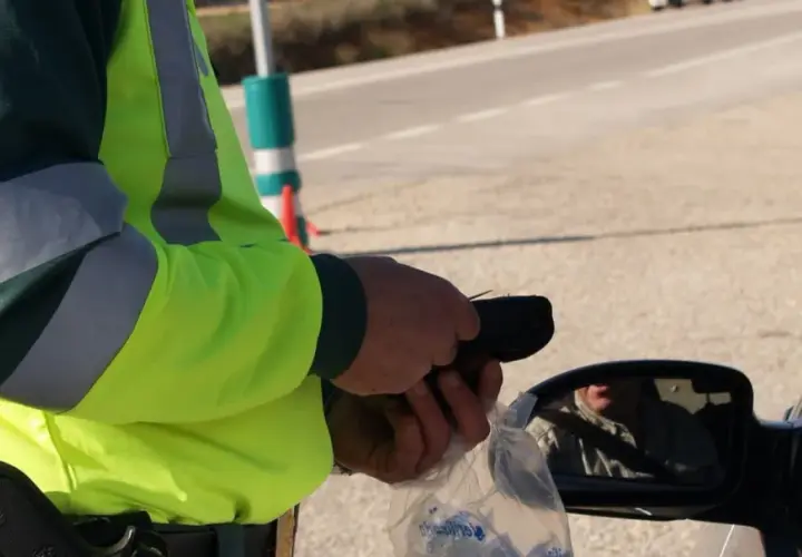 Policjant w kamizelce odblaskowej mierzy kierowcy trzeźwość. W Polsce obowiązują surowe przepisy dotyczące tego, ile promili można mieć we krwi.