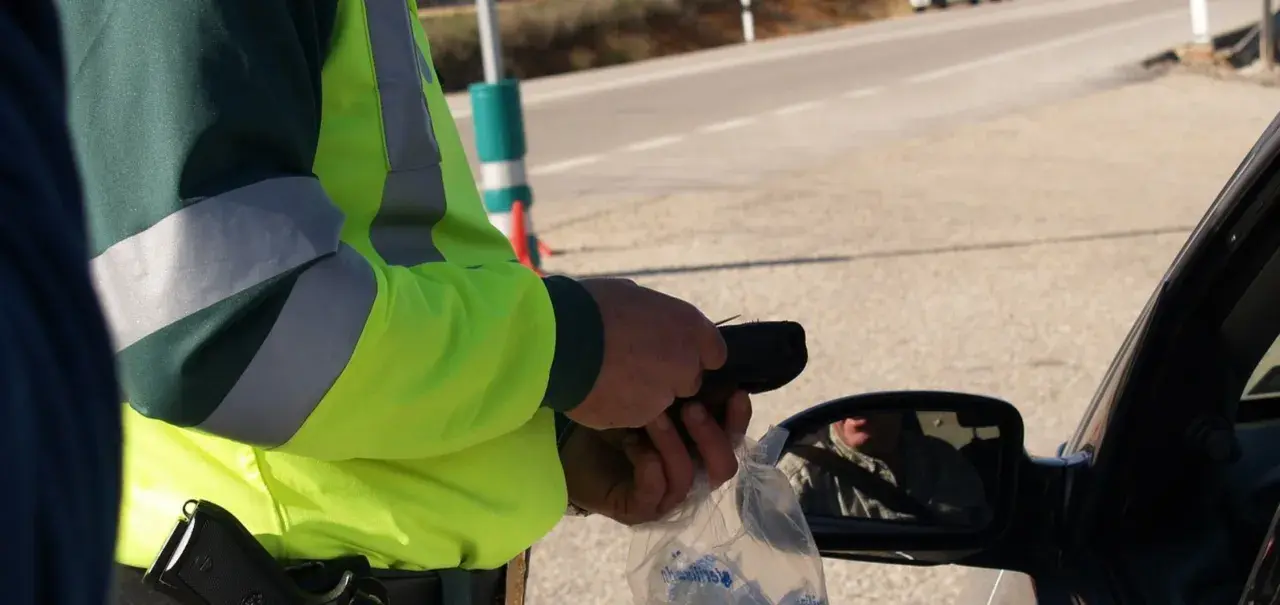 Policjant w kamizelce odblaskowej mierzy kierowcy trzeźwość. W Polsce obowiązują surowe przepisy dotyczące tego, ile promili można mieć we krwi.