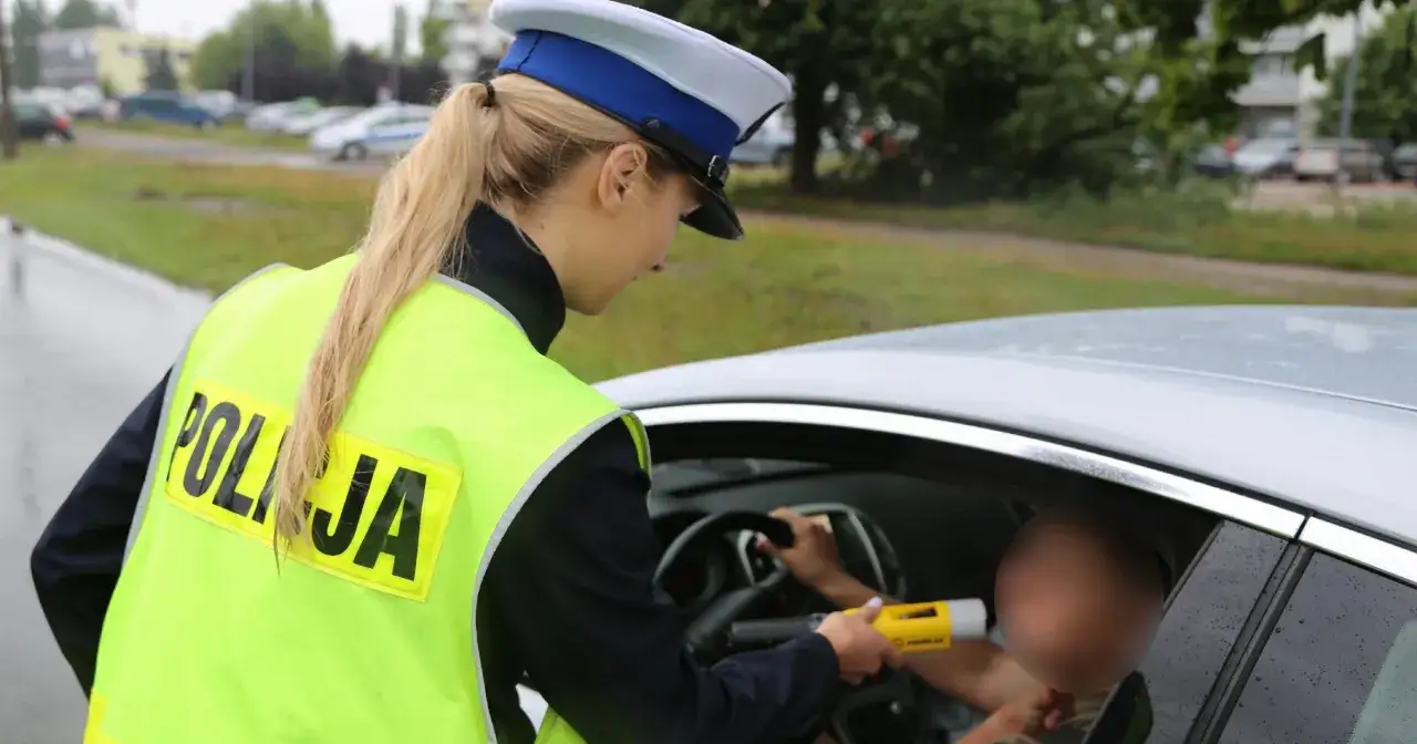 Policjantka kontroluje kierowcę alkomatem, sprawdzając dopuszczalną ilość alkoholu.