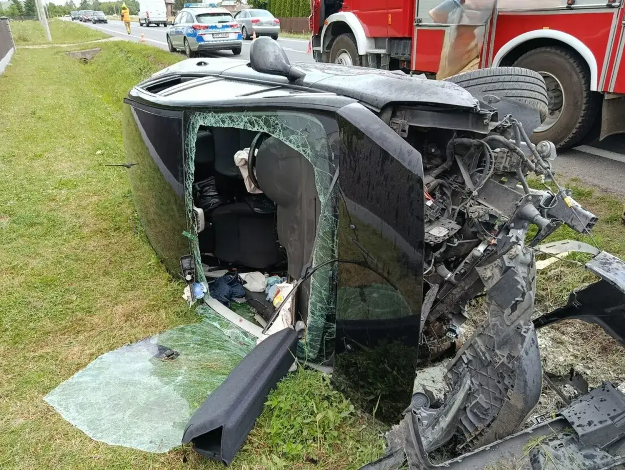 Wypadek drogowy w Polsce. Przewrócony czarny samochód, rozbite szyby, widoczna straż pożarna. Czy kierowca był pod wpływem alkoholu? Ile promili w Polsce to limit?